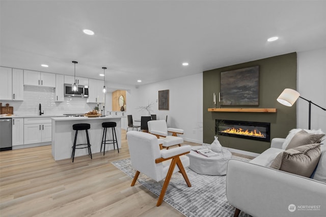 living room with a fireplace, sink, and light hardwood / wood-style floors