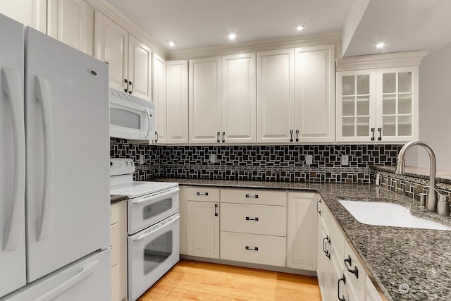 kitchen with white cabinetry, sink, dark stone countertops, and white appliances