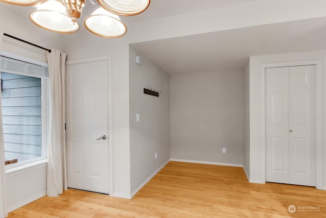 unfurnished bedroom featuring a chandelier and light wood-type flooring