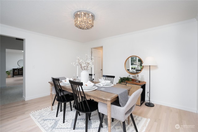 dining space featuring a chandelier, ornamental molding, and light hardwood / wood-style floors