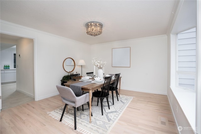 dining area featuring ornamental molding, light wood-type flooring, and a notable chandelier