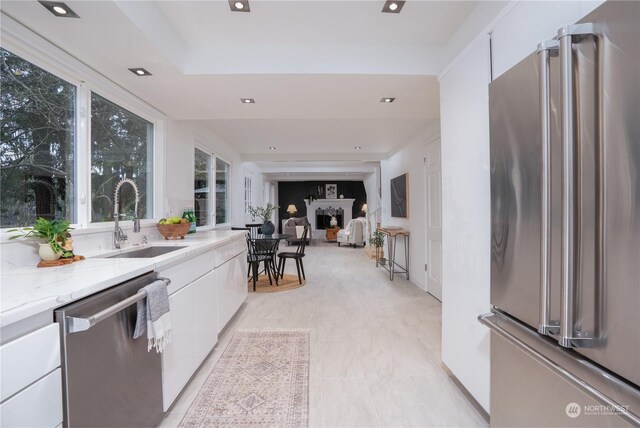 kitchen featuring sink, stainless steel appliances, light stone counters, and white cabinetry