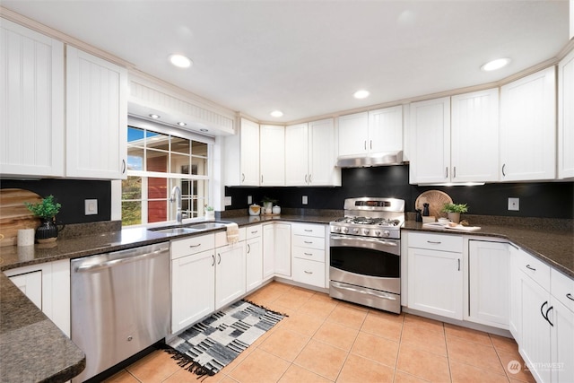 kitchen with appliances with stainless steel finishes, white cabinetry, sink, and light tile patterned floors