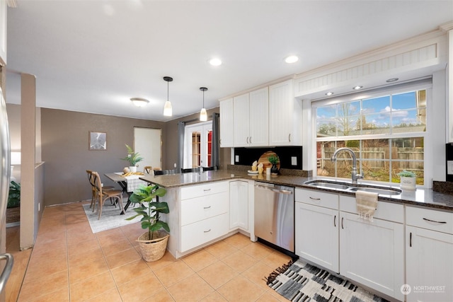 kitchen featuring dark stone countertops, kitchen peninsula, sink, decorative light fixtures, and stainless steel dishwasher