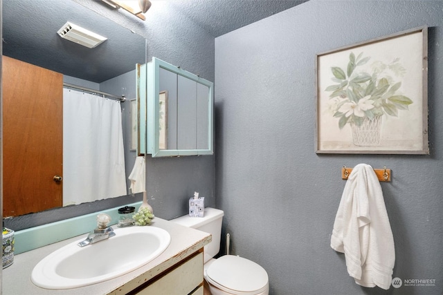 bathroom with toilet, vanity, and a textured ceiling