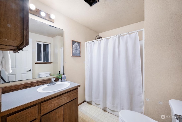 bathroom featuring a textured ceiling, vanity, and toilet