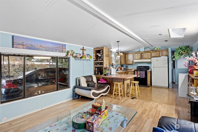 living room with light wood-type flooring and vaulted ceiling with skylight