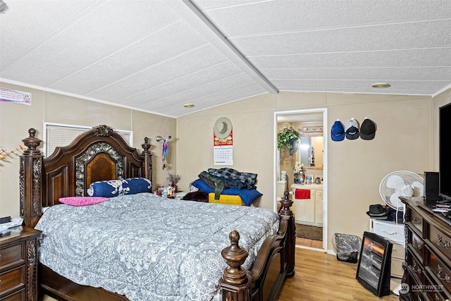 bedroom with ensuite bath, light wood-type flooring, and lofted ceiling