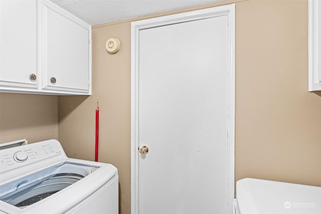 laundry area with washer / dryer, a textured ceiling, and cabinets