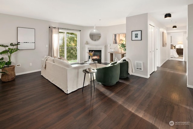 living room featuring dark wood-type flooring and a tile fireplace