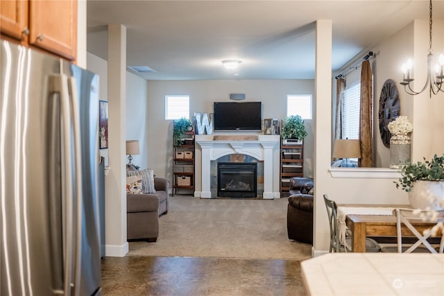 carpeted living room featuring a tile fireplace and a notable chandelier