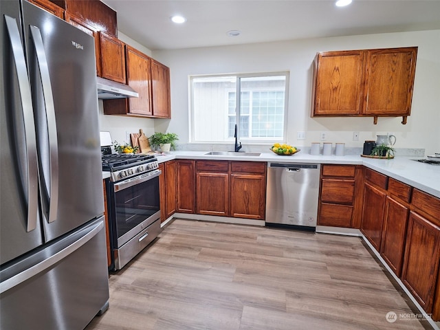 kitchen featuring light wood finished floors, light countertops, appliances with stainless steel finishes, a sink, and under cabinet range hood