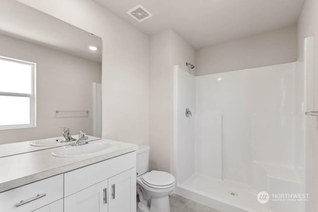 bathroom with walk in shower, vanity, and toilet