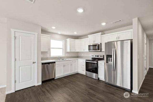 kitchen with dark wood-type flooring, appliances with stainless steel finishes, sink, and white cabinets