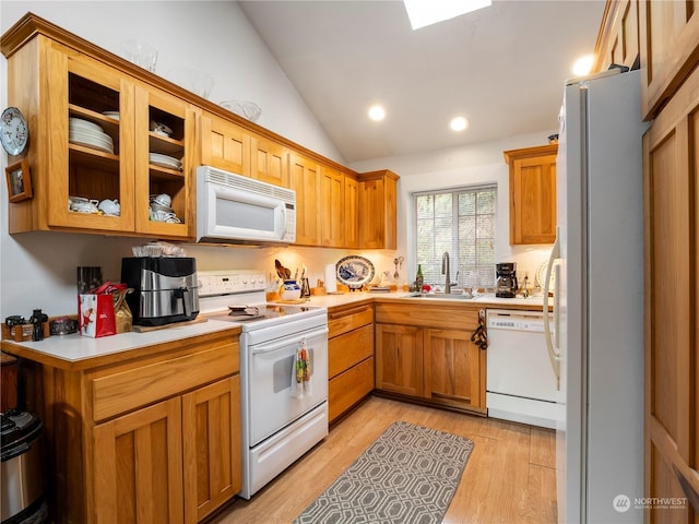 kitchen featuring lofted ceiling, white appliances, sink, and light hardwood / wood-style flooring