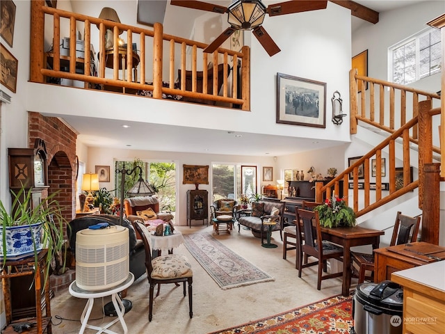 living room featuring beam ceiling, a towering ceiling, carpet floors, and ceiling fan