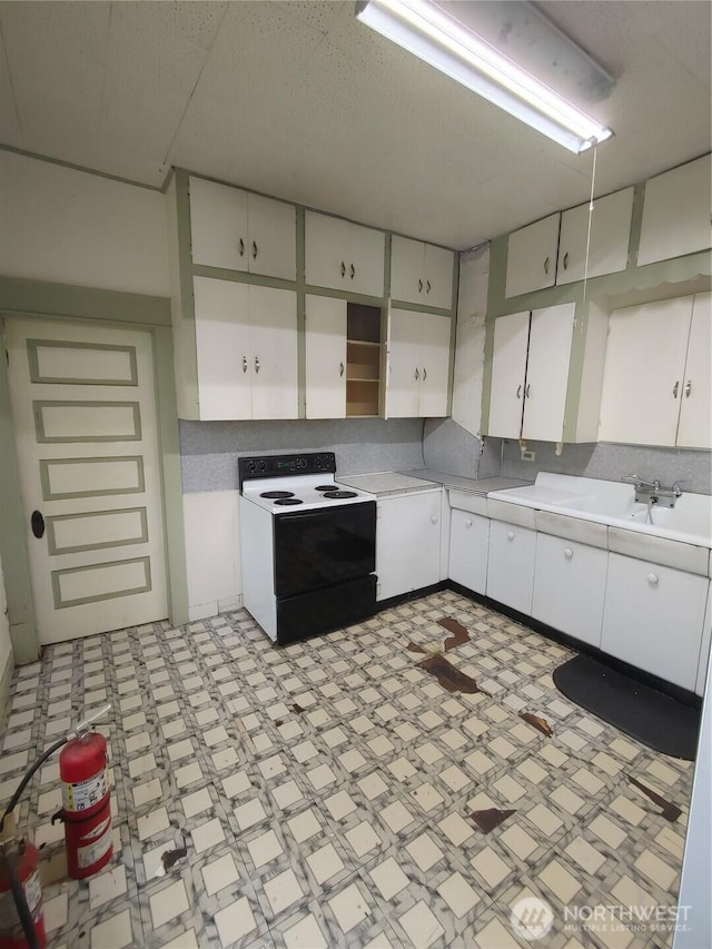 307 S Exchange St, Aberdeen, WA 98520 - kitchen with open shelves, light countertops, electric stove, white cabinetry, and light floors