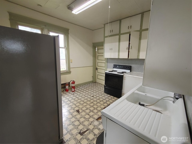 307 S Exchange St, Aberdeen, WA 98520 - kitchen with freestanding refrigerator, light floors, light countertops, white cabinetry, and electric stove