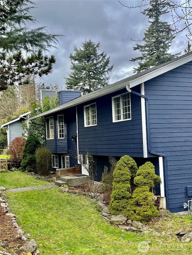 split foyer home featuring a chimney and a front lawn