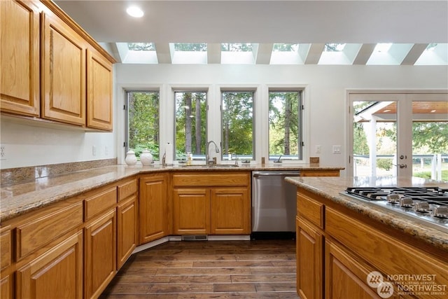 kitchen featuring sink, a healthy amount of sunlight, light stone counters, dark hardwood / wood-style floors, and appliances with stainless steel finishes