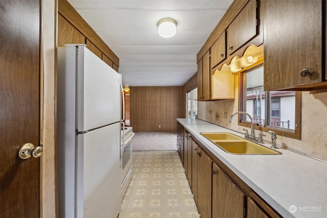 kitchen featuring white appliances, wood walls, and sink