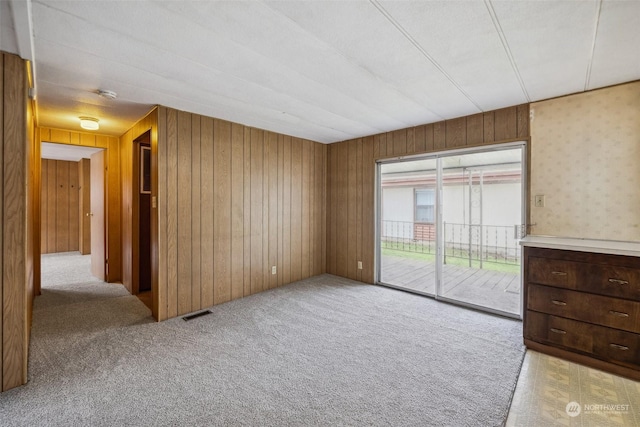 spare room featuring wood walls and light carpet