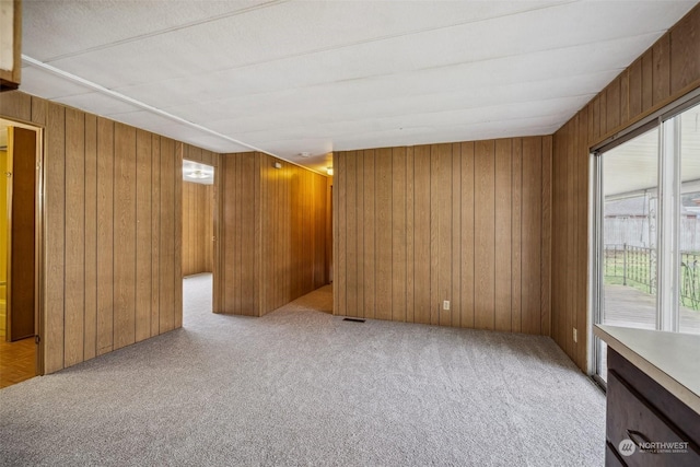 unfurnished room with wooden walls and light carpet