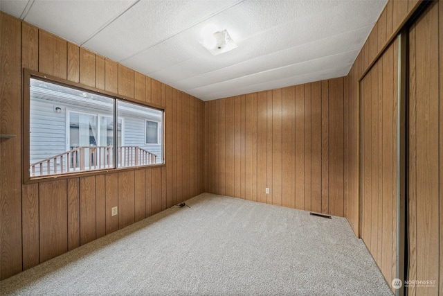 empty room with wooden walls and carpet floors