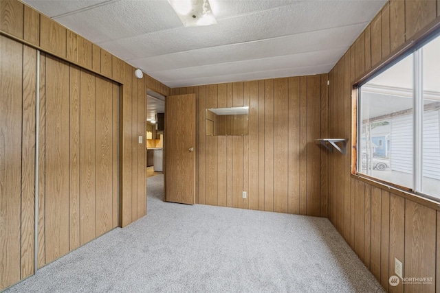 bedroom featuring light carpet, a closet, and wood walls