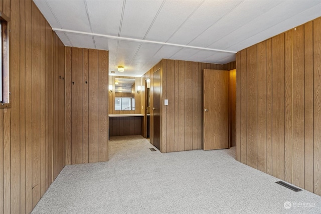 hallway with light colored carpet and wood walls