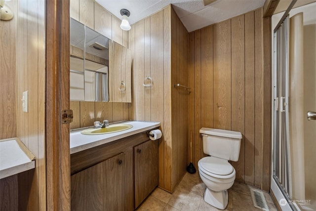 bathroom featuring toilet, tile patterned flooring, vanity, and wood walls