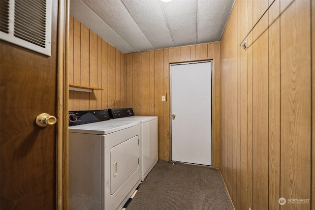 laundry room featuring washer and dryer, wood walls, a textured ceiling, and dark colored carpet