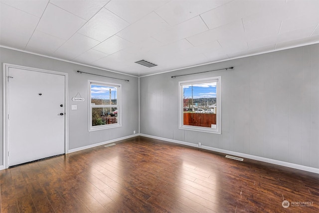 entrance foyer with ornamental molding, a healthy amount of sunlight, and dark hardwood / wood-style floors