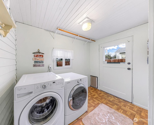 clothes washing area with separate washer and dryer, wood ceiling, and light parquet flooring