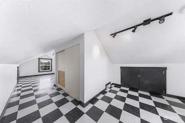 additional living space featuring lofted ceiling and a textured ceiling