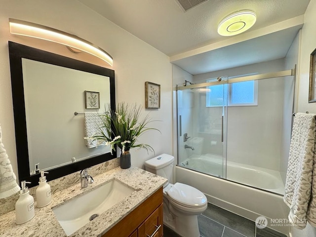 full bathroom featuring toilet, bath / shower combo with glass door, vanity, tile patterned floors, and a textured ceiling