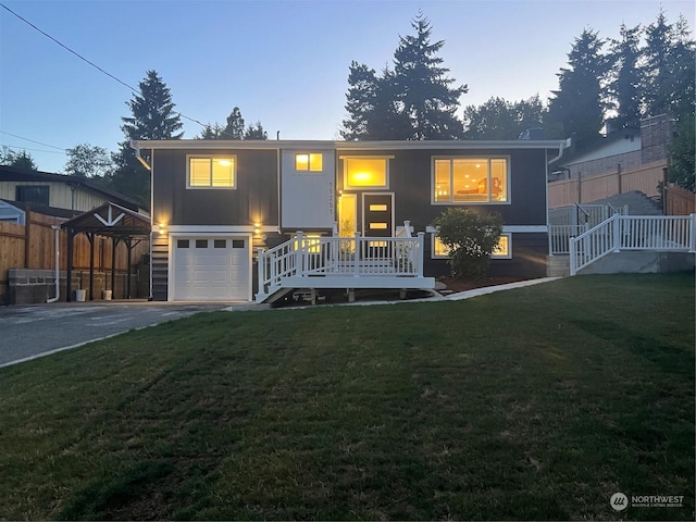 bi-level home with a garage, a lawn, and a carport