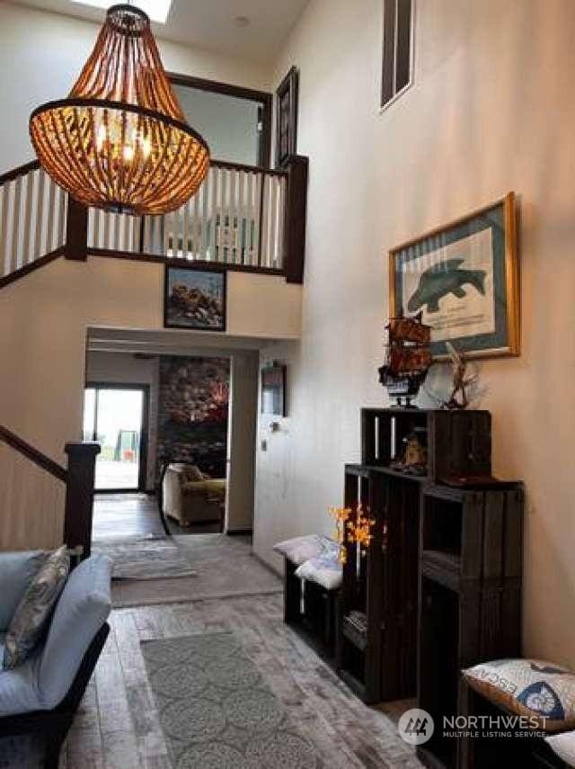 entryway featuring a notable chandelier, wood-type flooring, and a towering ceiling