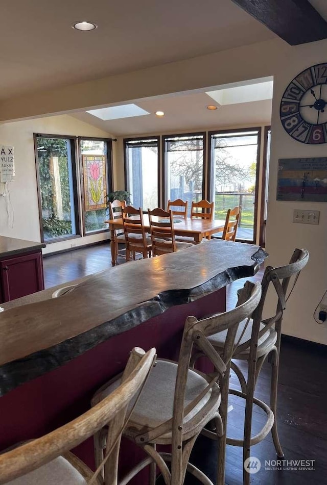 dining space featuring a skylight, plenty of natural light, and dark hardwood / wood-style floors