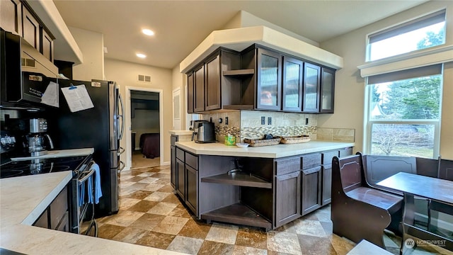 kitchen featuring electric range oven, dark brown cabinets, and decorative backsplash