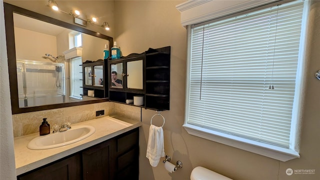 bathroom with toilet, a shower with door, and vanity