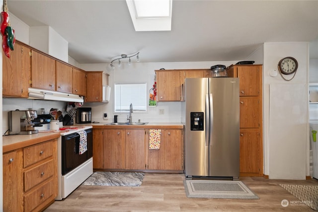 kitchen with stainless steel fridge, light wood-type flooring, a skylight, white range with electric stovetop, and sink