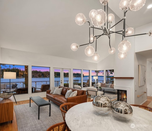 dining area with hardwood / wood-style floors, a notable chandelier, a water view, and lofted ceiling