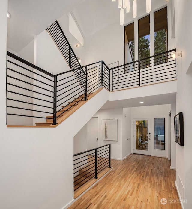 stairway featuring a towering ceiling and wood-type flooring