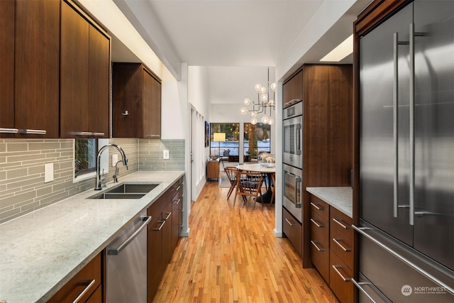 kitchen featuring a chandelier, hanging light fixtures, stainless steel appliances, decorative backsplash, and sink