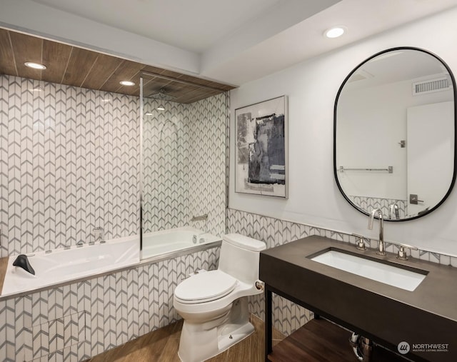 full bathroom with sink, wood-type flooring, toilet, and tiled shower / bath combo