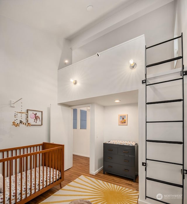 bedroom with light hardwood / wood-style floors and beamed ceiling