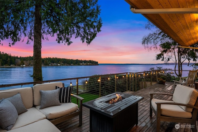 deck at dusk featuring an outdoor living space with a fire pit and a water view