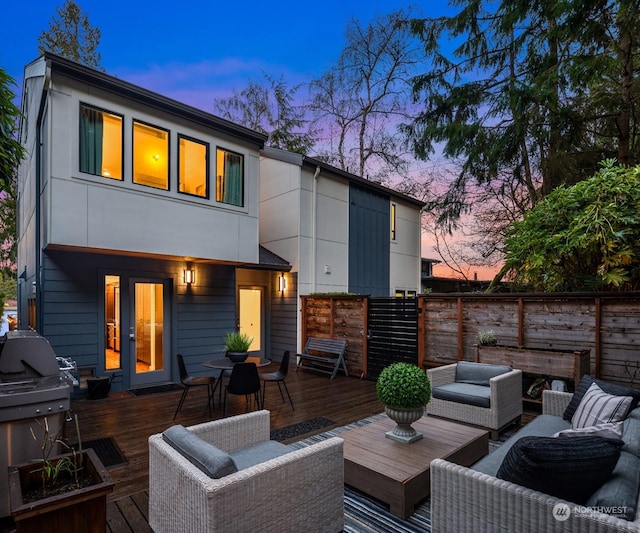 back house at dusk featuring a deck and outdoor lounge area