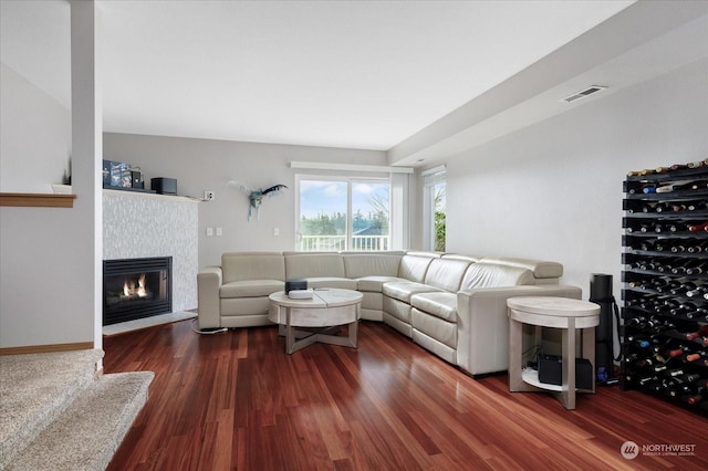 living room with dark hardwood / wood-style flooring and a tiled fireplace